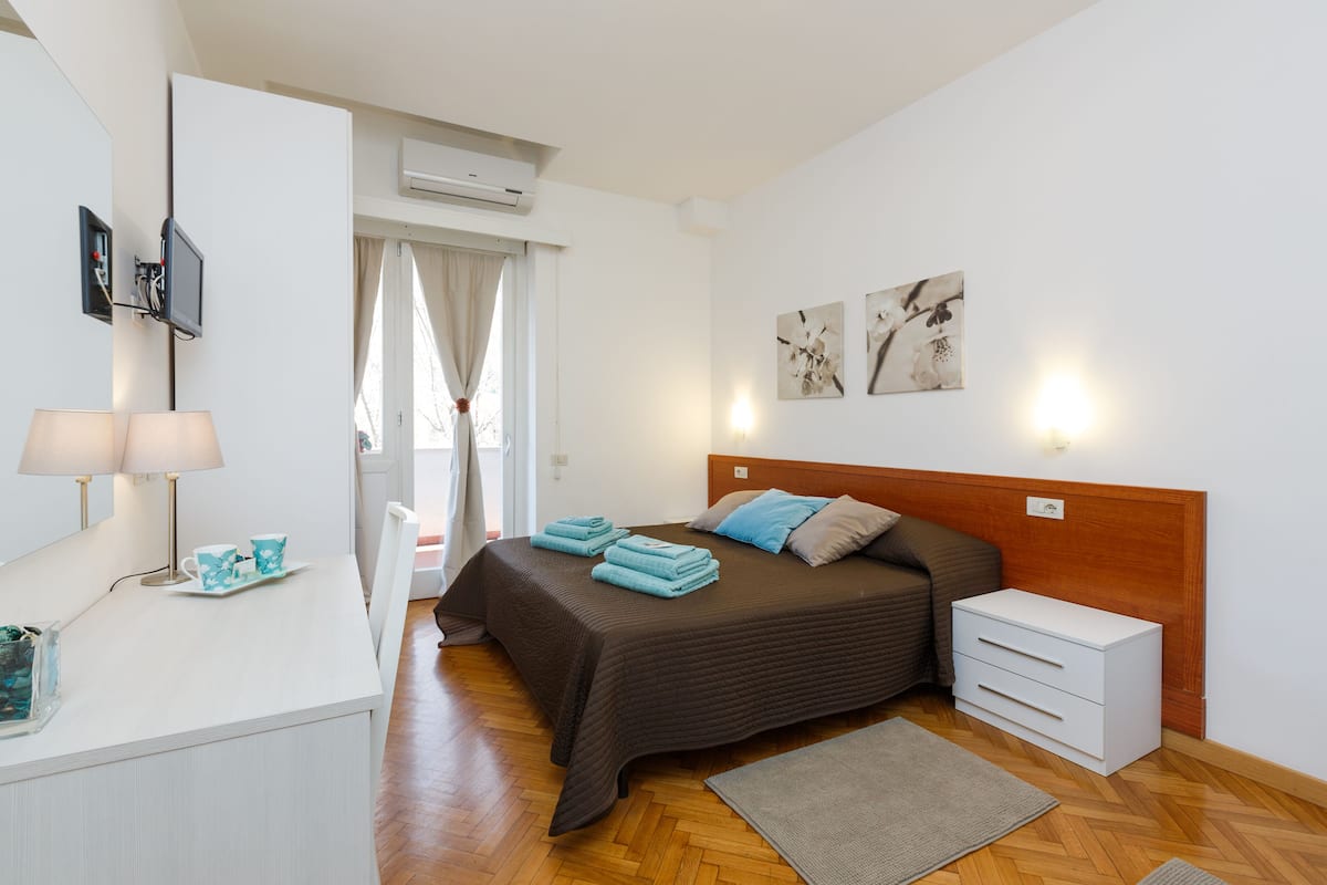 A bedroom with a bed, bedside table, and a mirror.