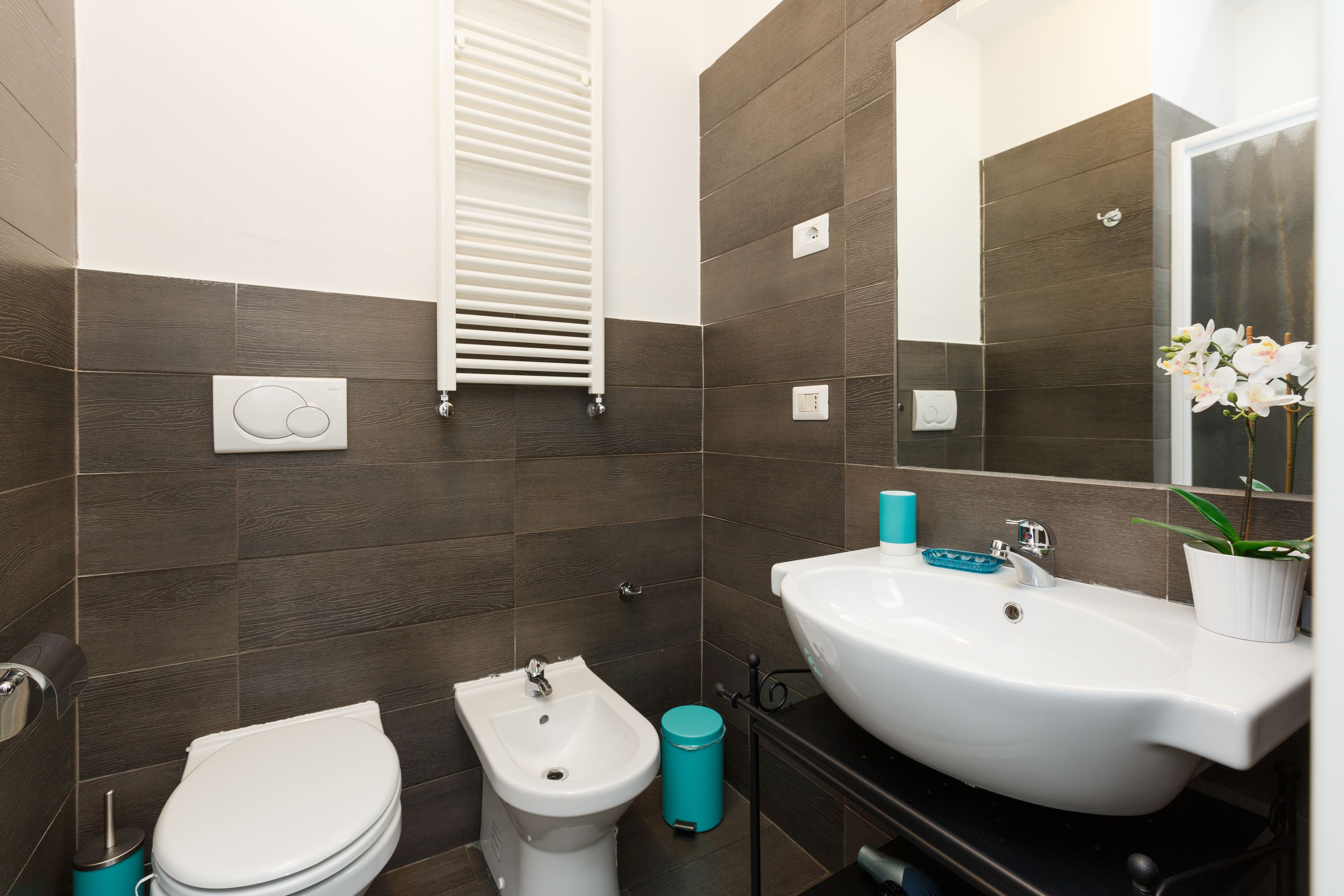 Ein modernes Badezimmer mit Bidet, Toilette, Waschbecken und Spiegel.