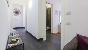 Un interior modern amb una taula de cafè de vidre, un sofà gris i un passadís que condueix a un bany.