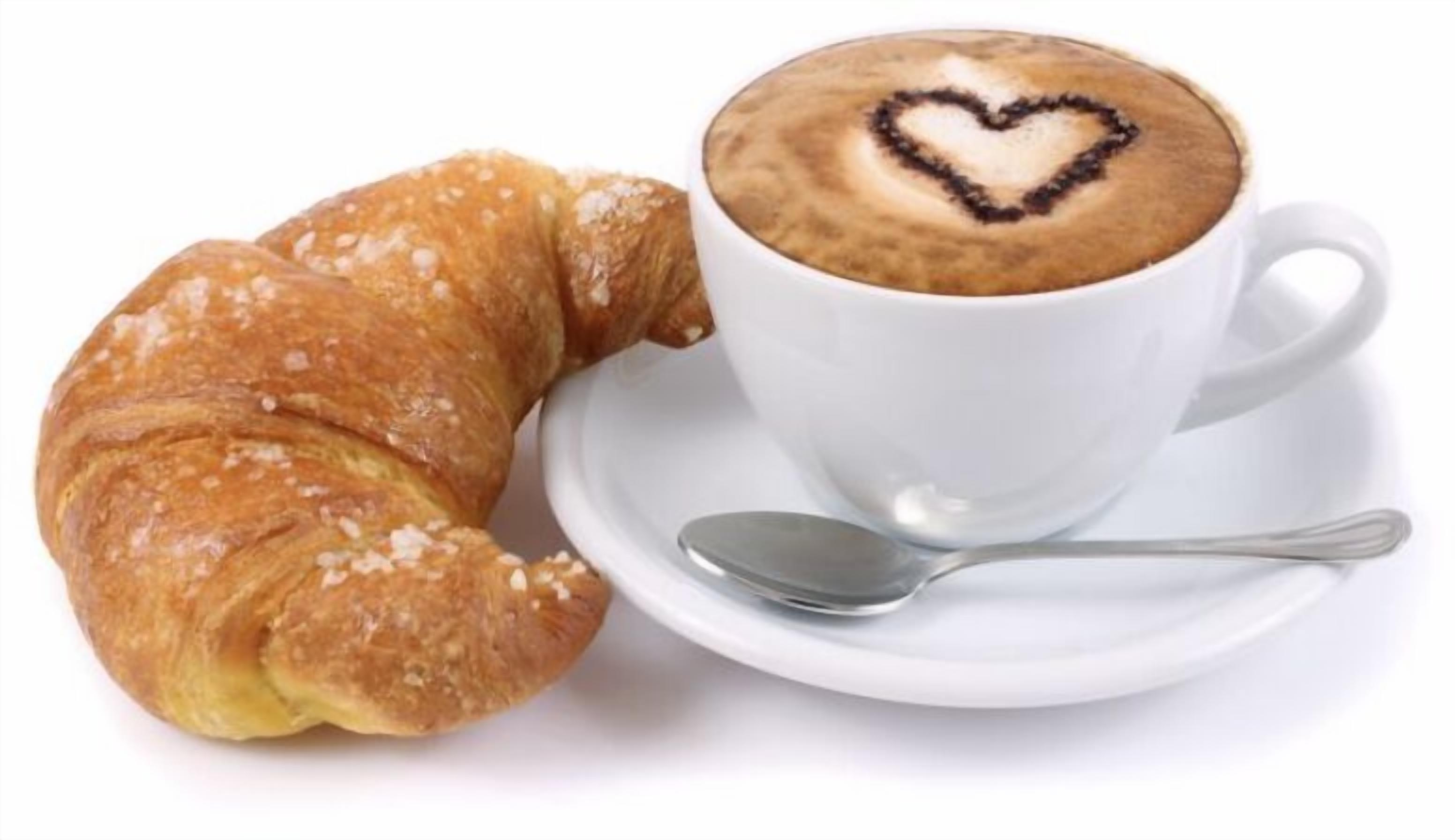Un croissant y una taza de café con un diseño de corazón en la espuma.
