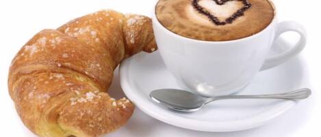 Un croissant y una taza de café con un diseño de corazón en la espuma.