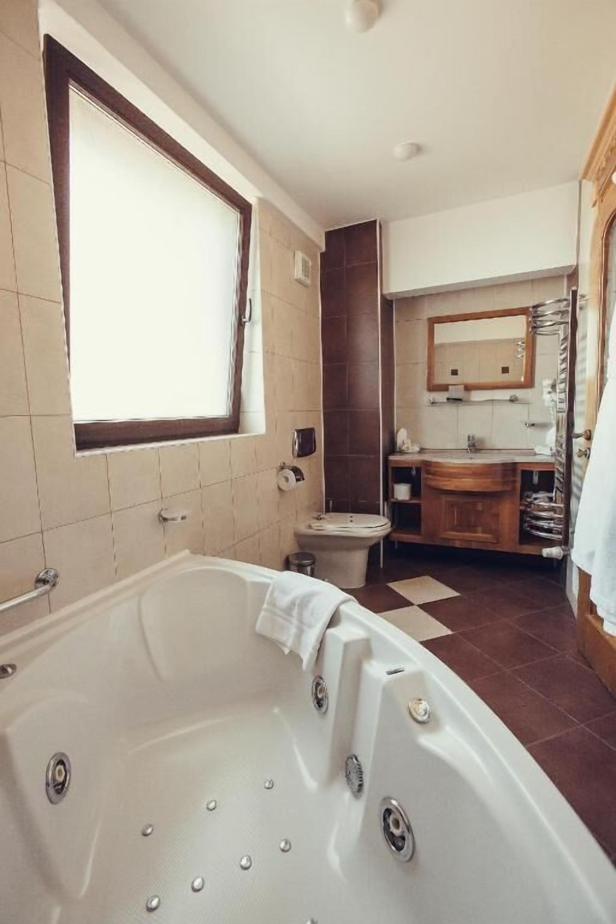 A bathroom with a large bathtub, a toilet, a sink, and a mirror.