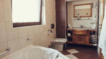 A bathroom with a large bathtub, a toilet, a sink, and a mirror.