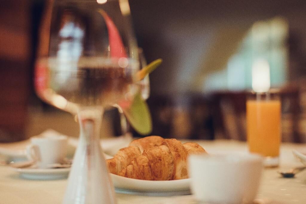 A breakfast setting with croissants, a glass of orange juice, and a wine glass.