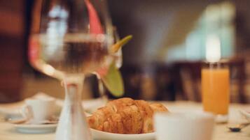 A breakfast setting with croissants, a glass of orange juice, and a wine glass.