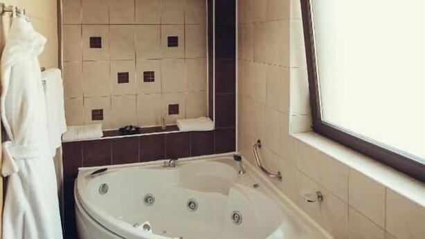 A modern bathroom with a freestanding bathtub, a large mirror, and a window. - Denisa Boutique (Brasov)