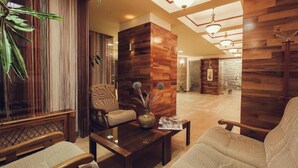 A modern lobby with wooden panel walls, a central seating area with a coffee table, and a large plant. - Denisa Boutique (Brasov)