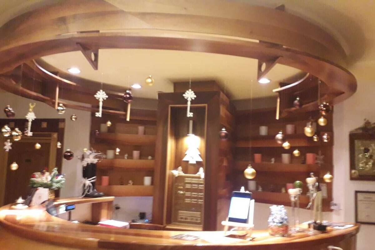 A reception desk with a wooden finish, surrounded by shelves with various items and a hanging light fixture.