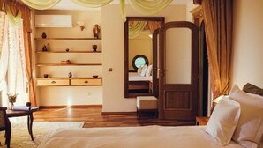 A bedroom with a large bed, a wooden wardrobe, a desk with a chair, and a shelf with decorative items. - Denisa Boutique (Brasov)