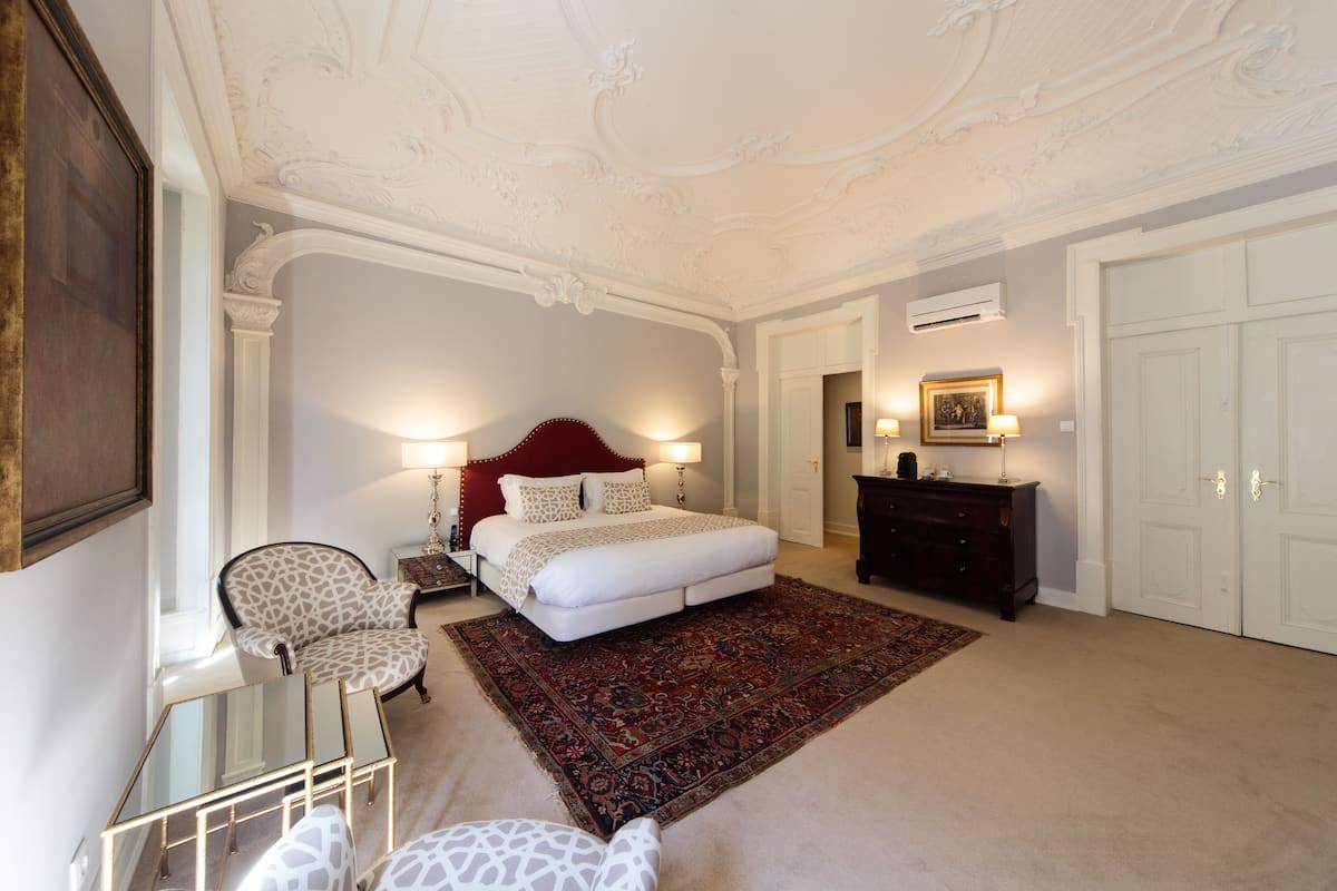 Une chambre à coucher avec un grand lit, une chaise, une commode et un miroir.