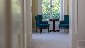 Un couloir menant à un balcon où se trouvent deux chaises et une table.