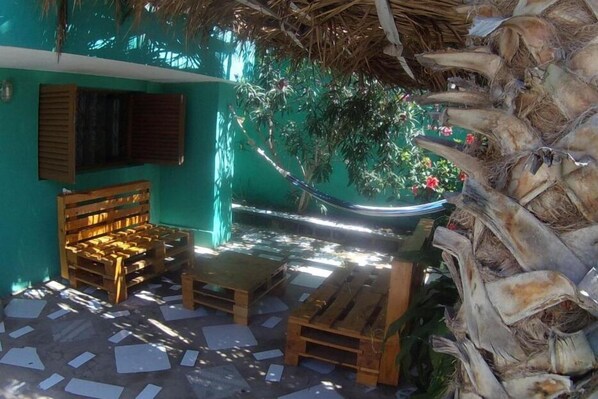 A room with a hammock, wooden furniture, and a green wall.