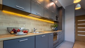 A modern kitchen with grey cabinets, a wooden countertop, a sink, and a microwave. - Absynt Apart Wierzbowa (Wroclaw)