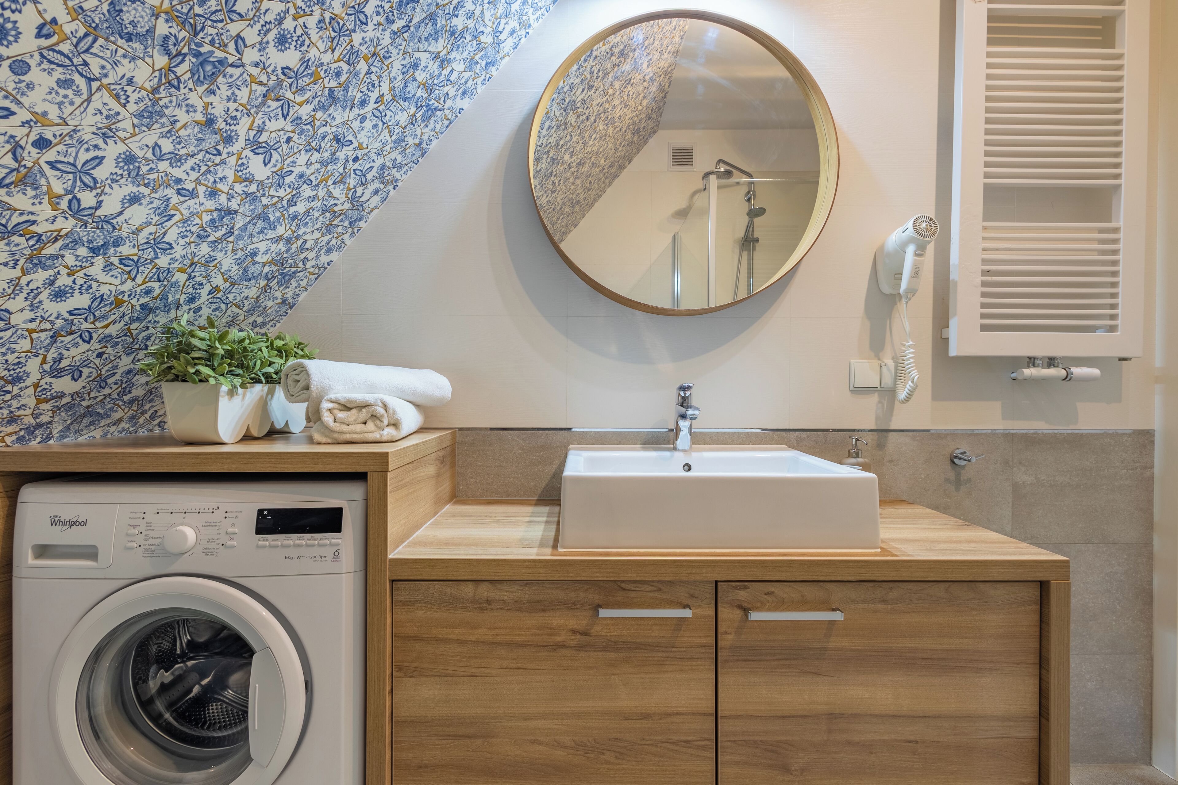 A modern bathroom with a built-in washer and dryer, a sink, and a mirror.