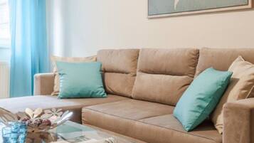 A modern living room with a beige sofa, a glass coffee table, and a world map artwork on the wall.