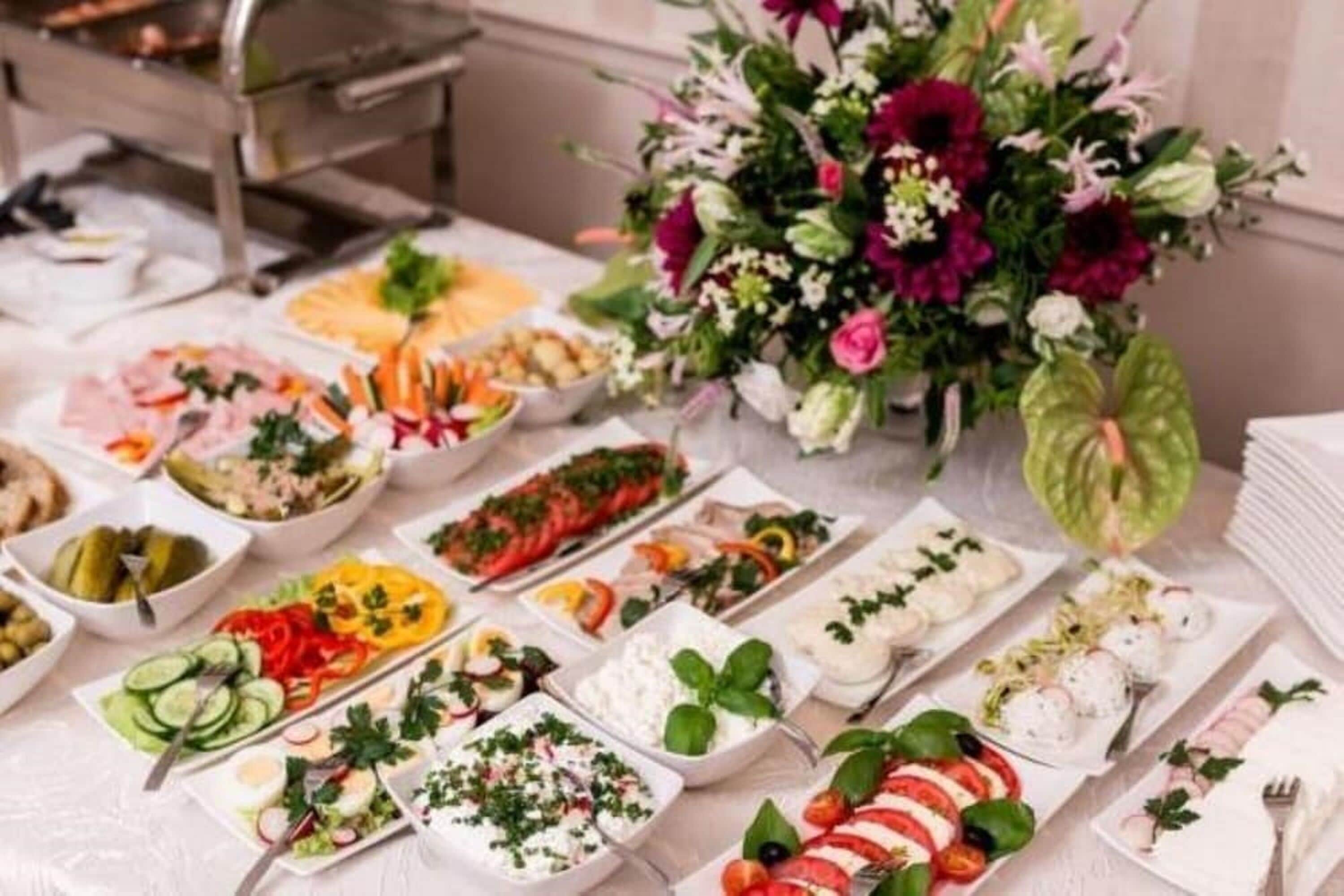 Ein reichhaltiges Buffet mit verschiedenen Speisen und einer großen Blumenkomposition.