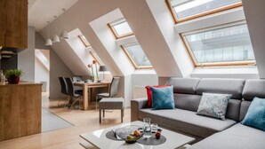 A modern loft apartment with skylights, a dining area, and a living space with a sofa and cushions. - Absynt Apart Wierzbowa (Wroclaw)