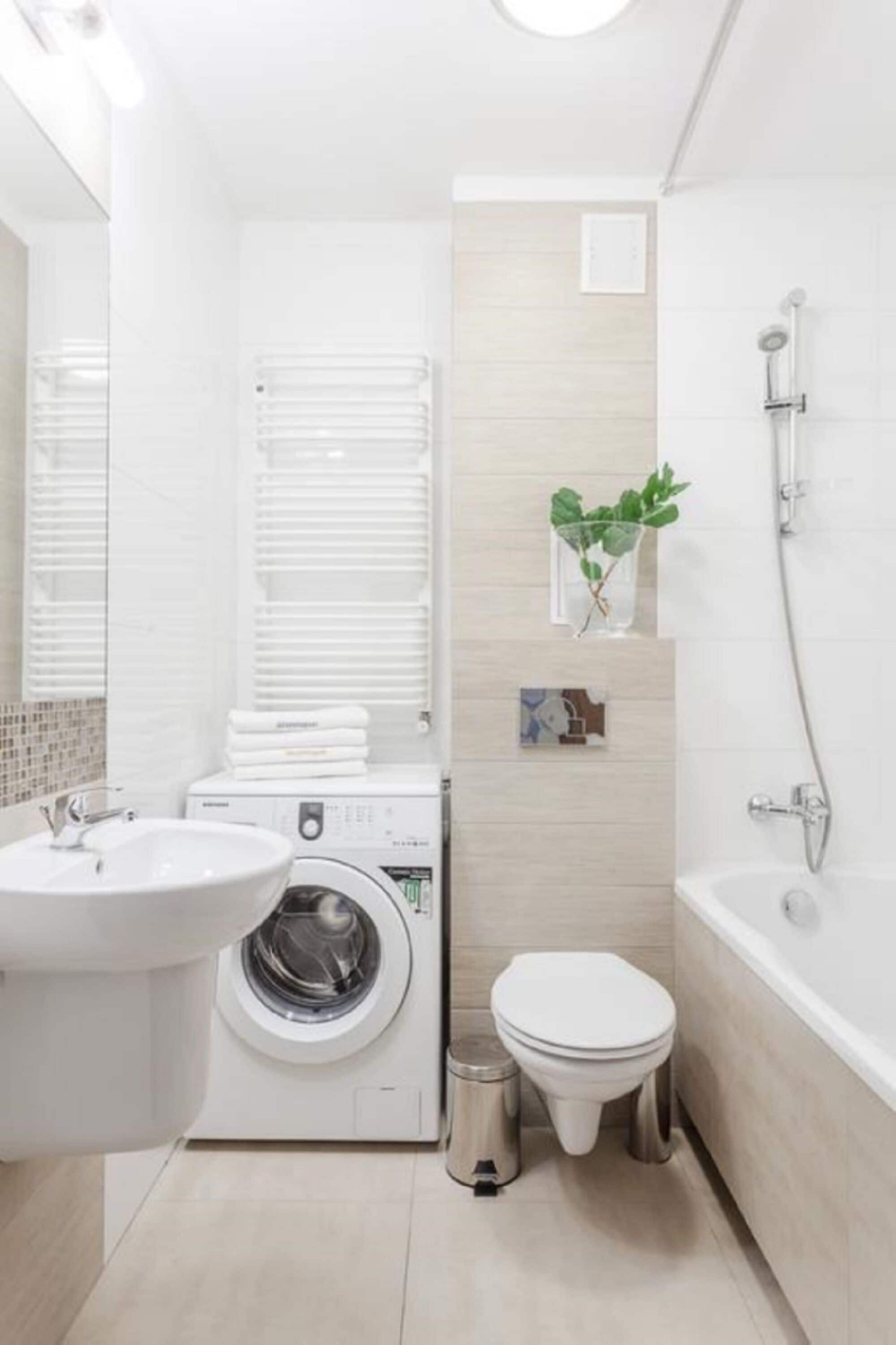 Un baño moderno con lavabo, lavadora, inodoro y ducha.