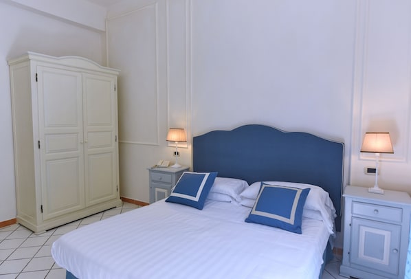 A neatly arranged bedroom with a bed, two bedside tables, a wardrobe, and two wall-mounted lamps. - Hotel Garden Riviera (Castellabate)