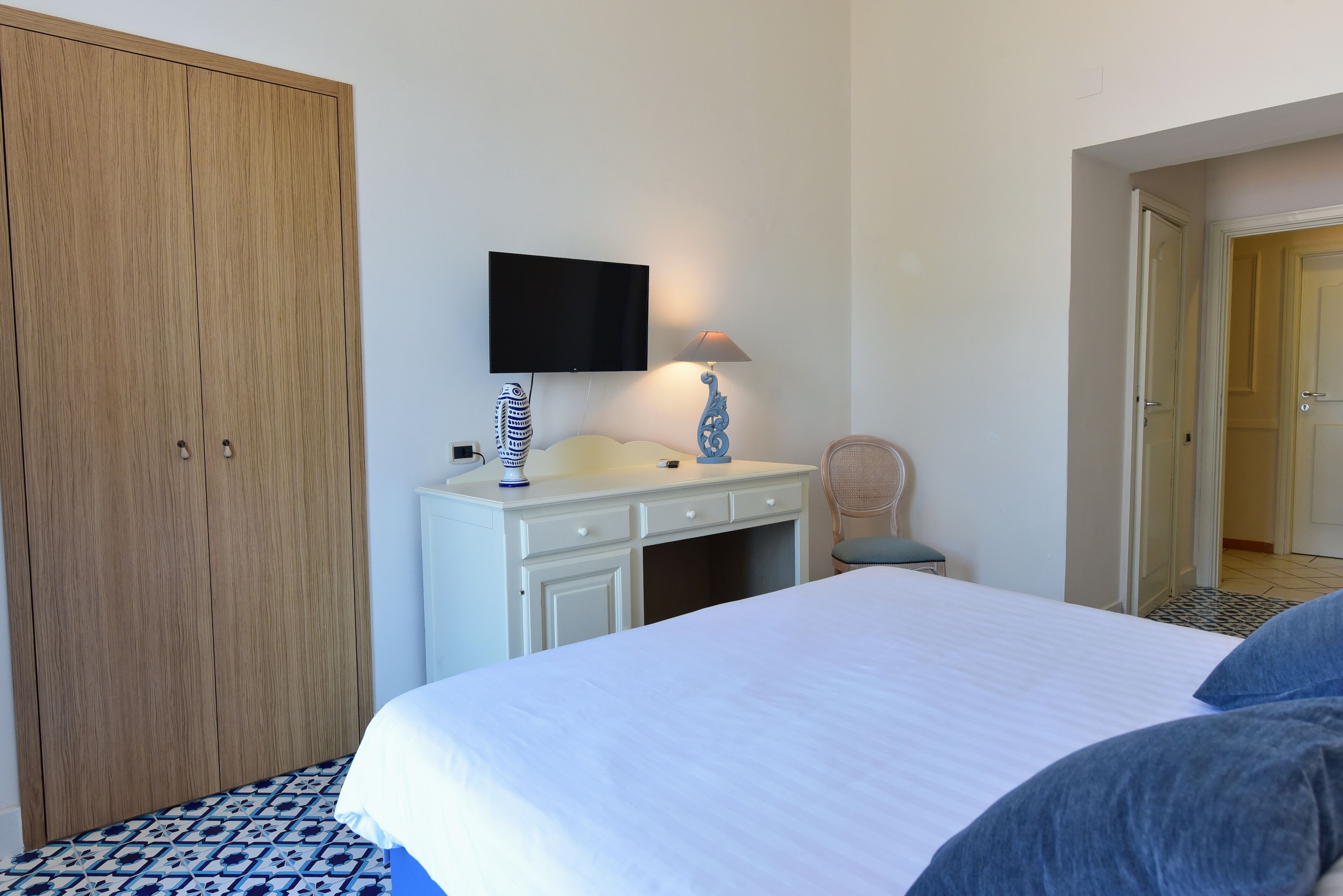 Une chambre à coucher comprenant un lit, une armoire, un bureau avec une lampe et un téléviseur.