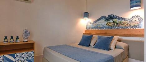 Ein Schlafzimmer mit einem Bett, einem Holzkopfende, einem Regal mit Dekoration und einer Wandmalerei.