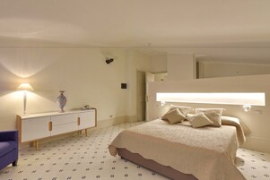 Un dormitorio con una cama, una mesita de noche, una lámpara y un aparador.