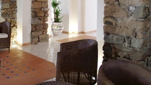 An interior with stone arches, wicker furniture, and a tiled floor.