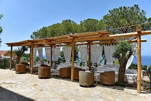 An outdoor seating area with wicker furniture and a pergola structure.