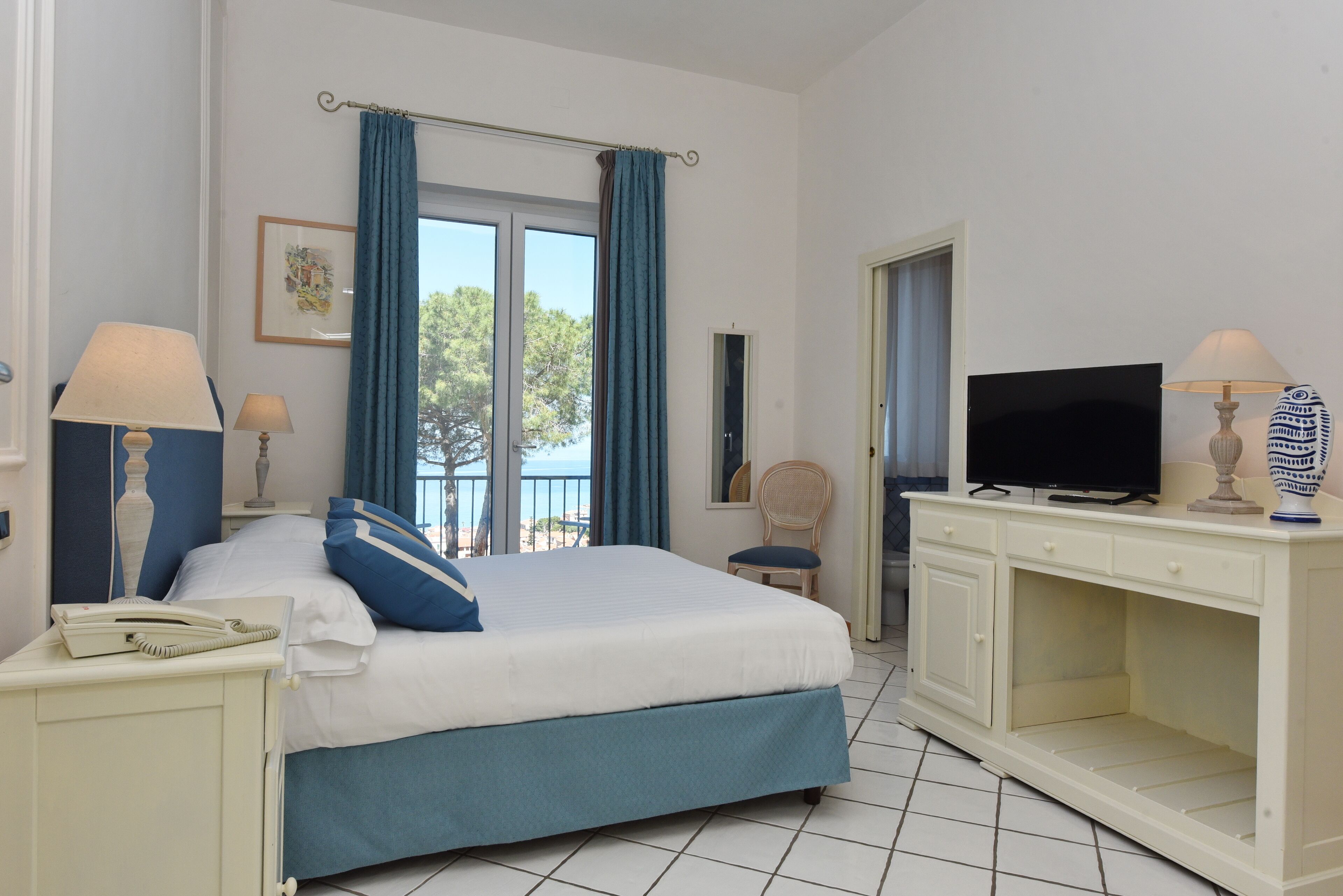 Una habitación de hotel con cama, televisor, escritorio y silla.