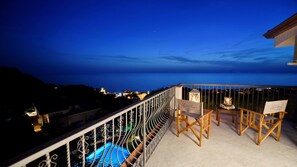 A balcony with a view of the sea, two wooden chairs, a table, and a sign reading "Hotel Garden Riviera".