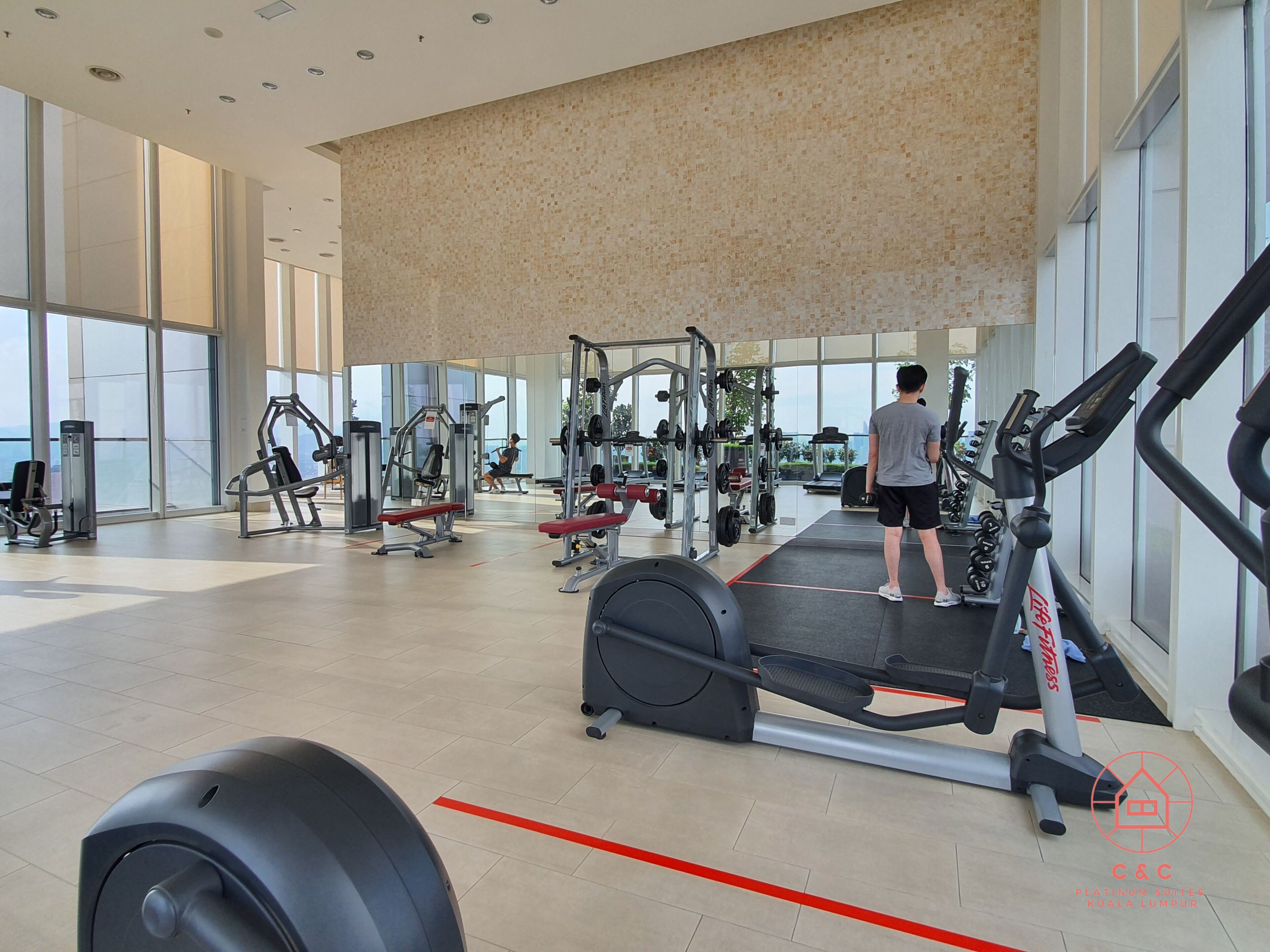 Un gimnasio moderno con diverso equipo de ejercicio, amplias ventanas y techo alto.