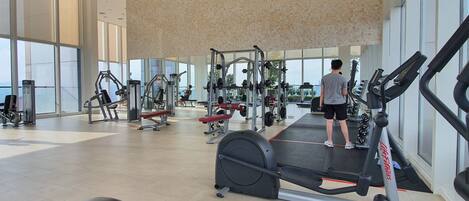 Un gimnasio moderno con diverso equipo de ejercicio, amplias ventanas y techo alto.