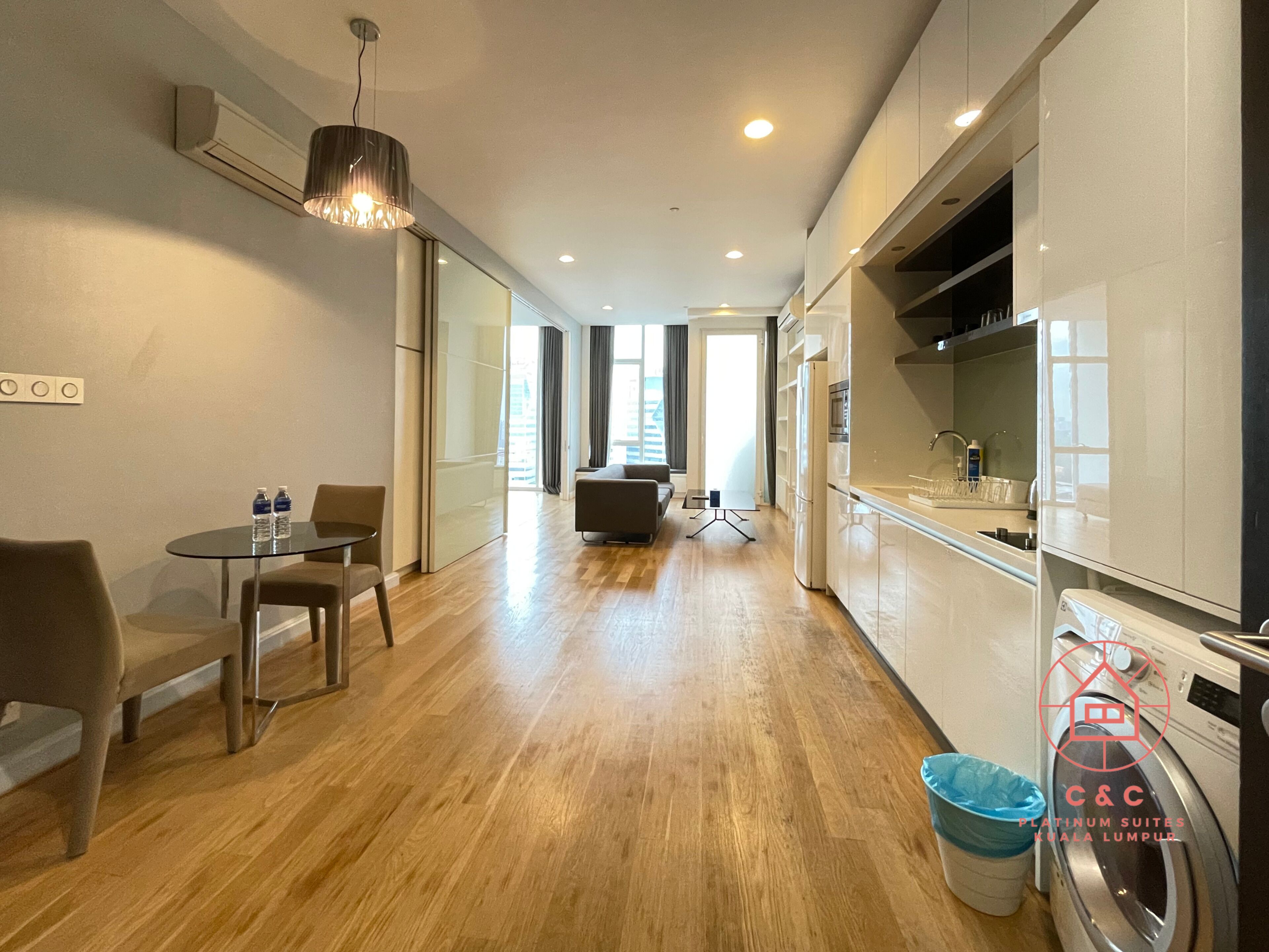 A modern apartment with a dining area, kitchen, and a view of the city.