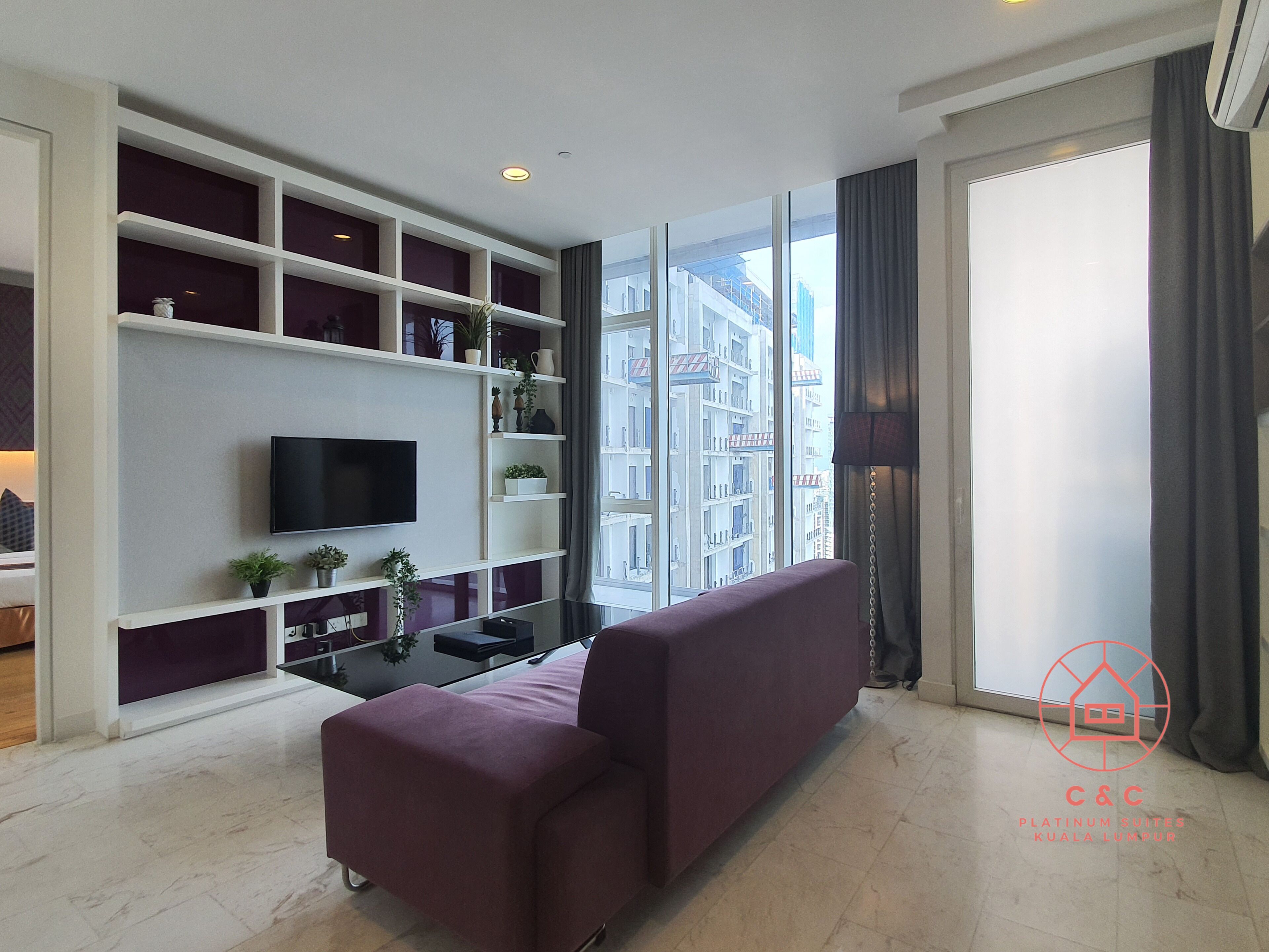 A modern living room with a large window, a flat-screen TV, and a purple sofa.