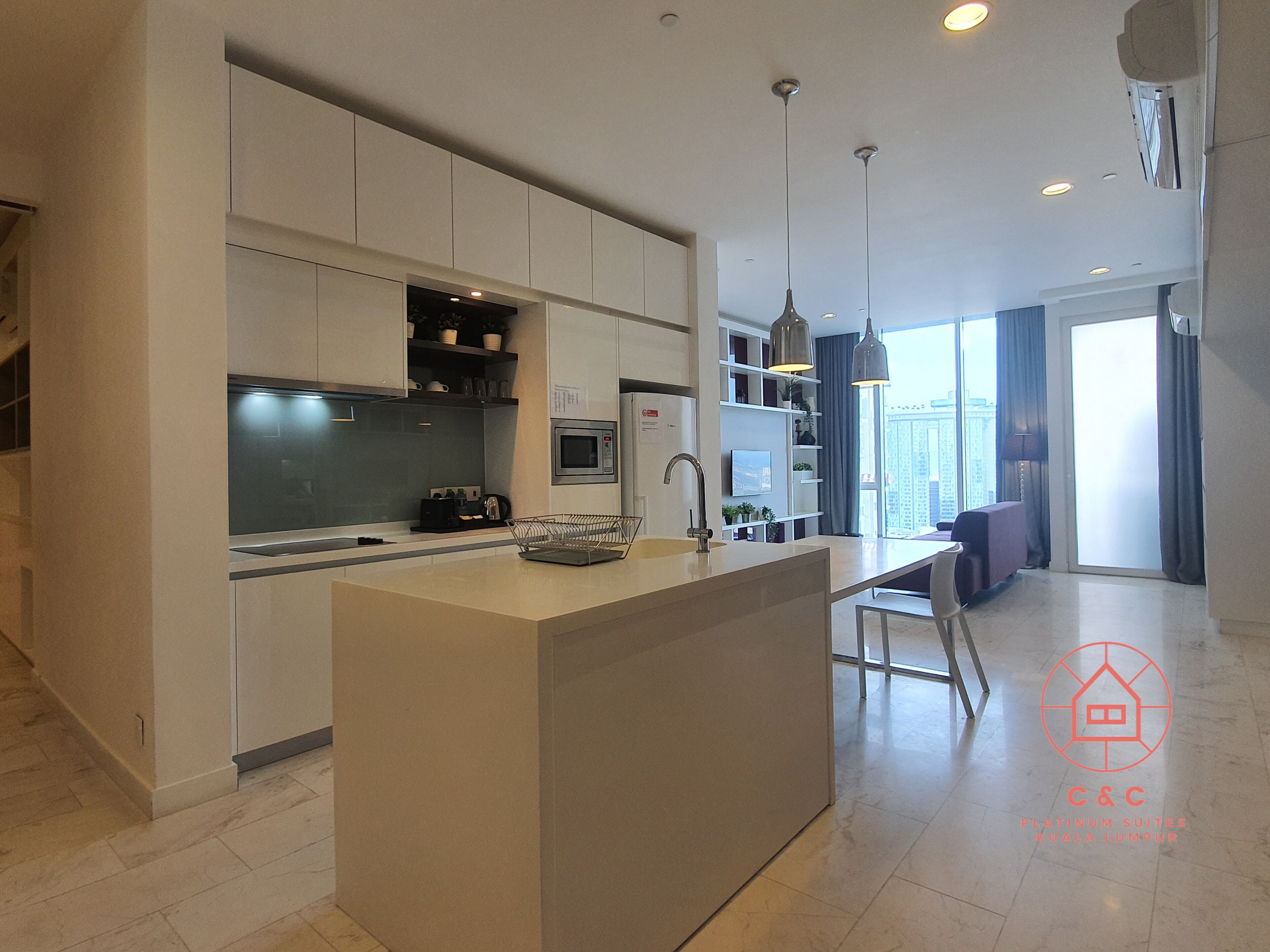 A modern kitchen with a central island, built-in appliances, and pendant lighting.