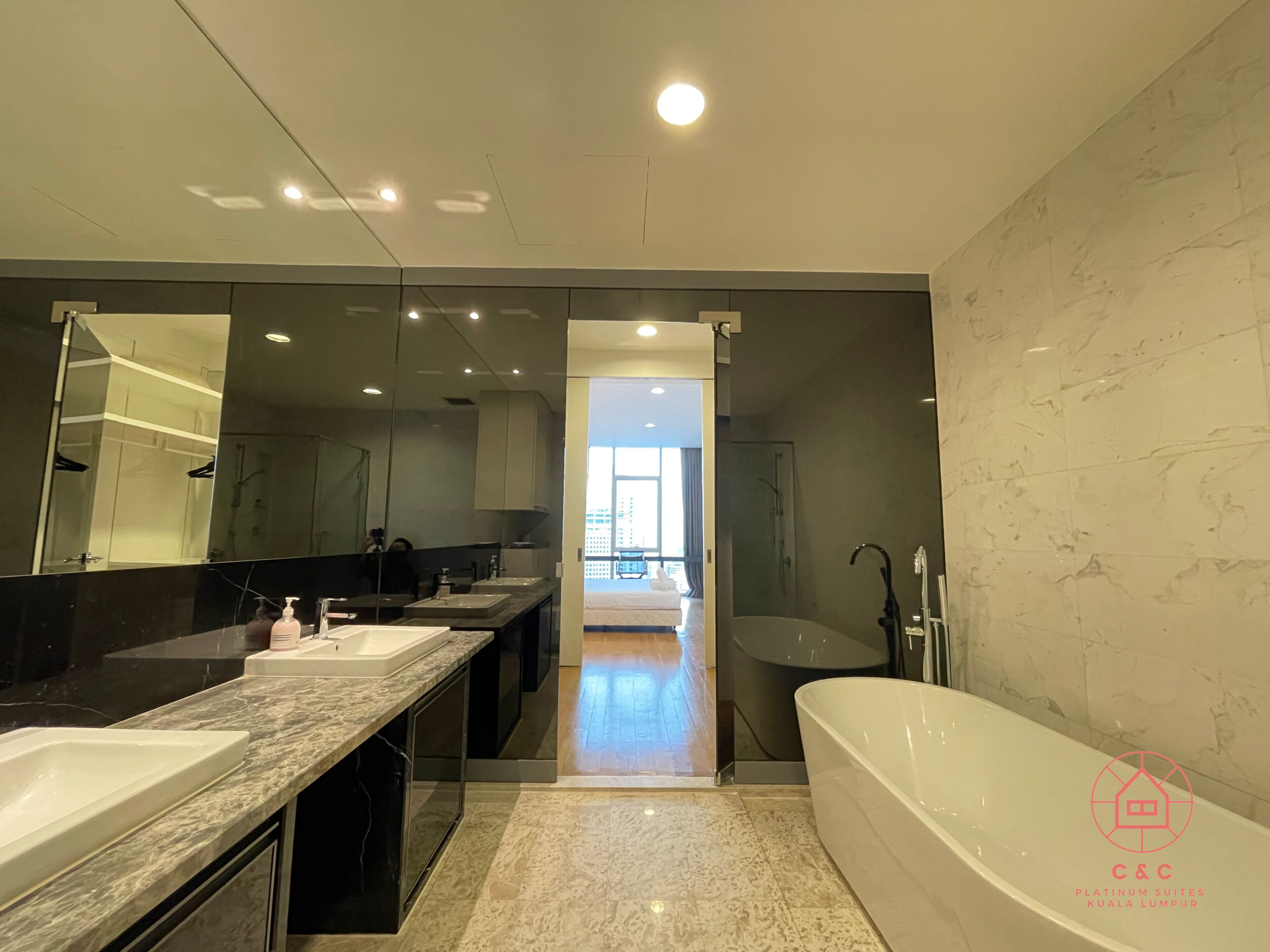 Een moderne badkamer met een grote spiegel, twee wasbakken, een bad en een douche.