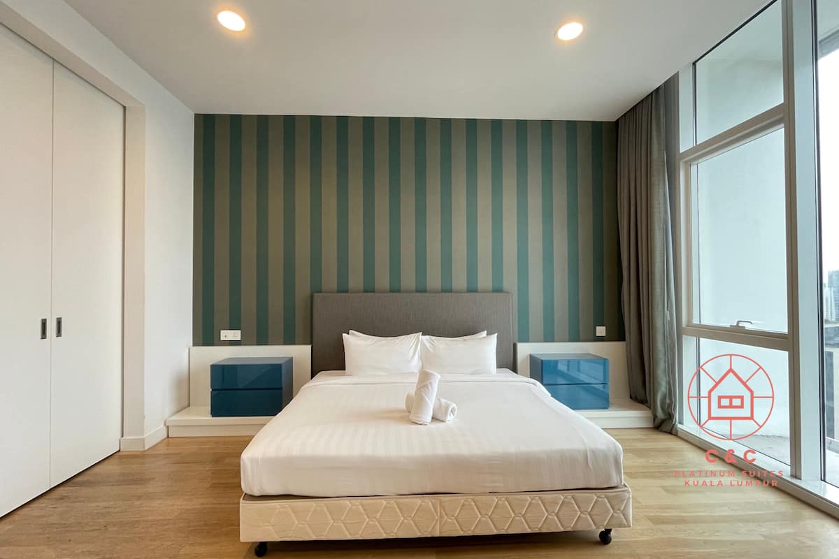 A modern hotel room with a large bed, two bedside tables, a headboard, and a large window offering a city view.