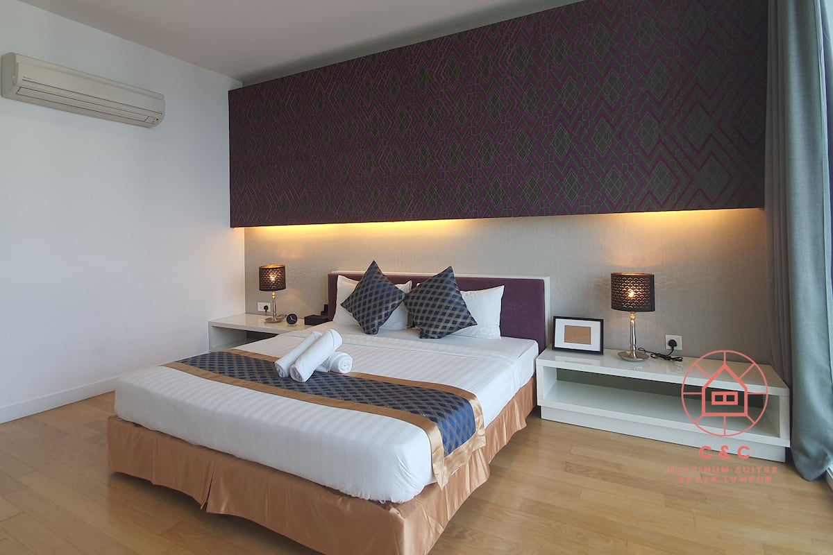A modern hotel room with a large bed, two bedside tables, and a patterned headboard.
