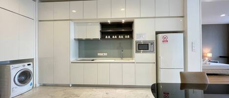 A modern kitchen with white cabinets, a built-in microwave, and a washing machine.