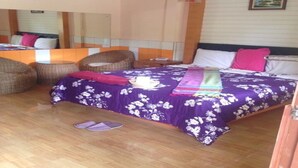Un dormitorio con una cama, dos sillas de mimbre, una mesita de noche y un espejo.
