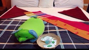 Una cama con un edredón escocés, un peluche verde y una cesta con objetos dentro.