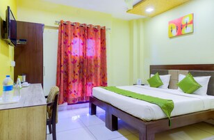 Habitación de hotel con cama, escritorio, silla, televisión y cortina de ducha.