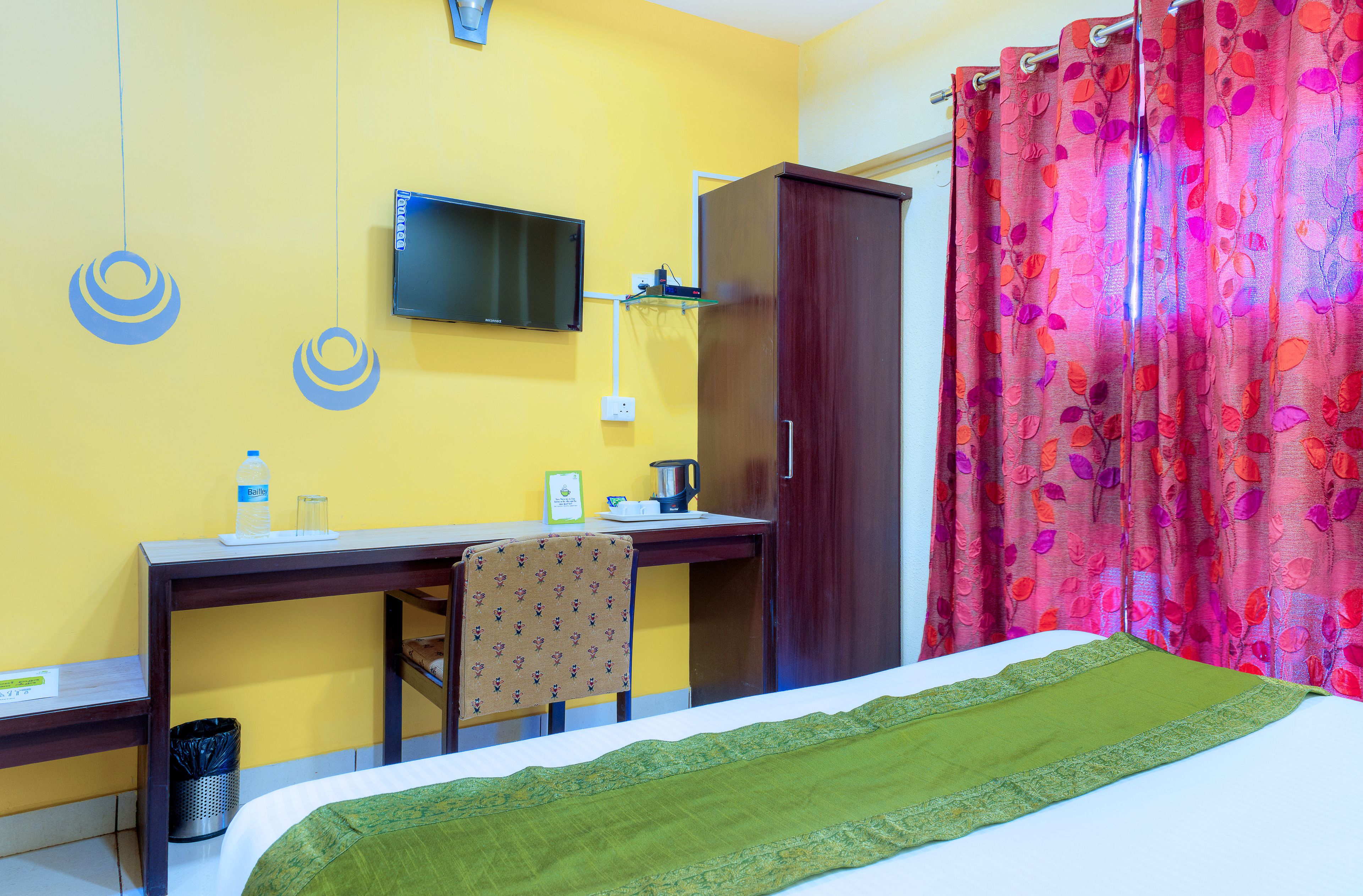 Una habitación de hotel con cama, escritorio, silla, televisor y armario.