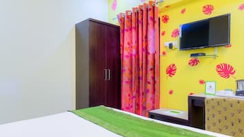 A room with a bed, a wardrobe, a TV mounted on the wall, and a desk with a chair.