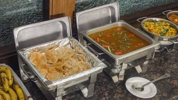 A buffet setup with various dishes and a tray of tortillas.
