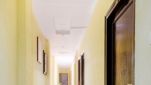 Ein Korridor mit Fliesenboden, einer Holztür rechts und einem gerahmten Bild an der linken Wand.