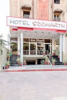 Entrada de un hotel con un letrero que dice "HOTEL SIDDHARTH" y una escalera que conduce a la entrada.