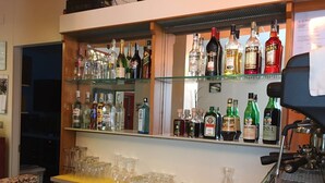 Zona de bar con estantes llenos de botellas de licor y vasos.