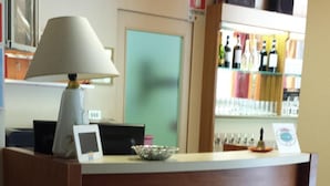 Un mostrador de recepción con una lámpara, un cuadro enmarcado y una vitrina de vidrio con botellas.