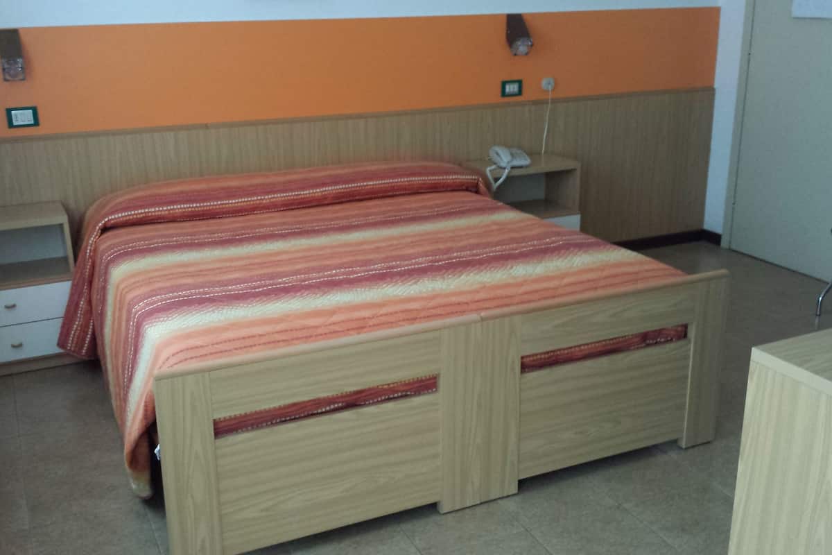A bedroom with a wooden bed, a desk, a chair, and a nightstand.